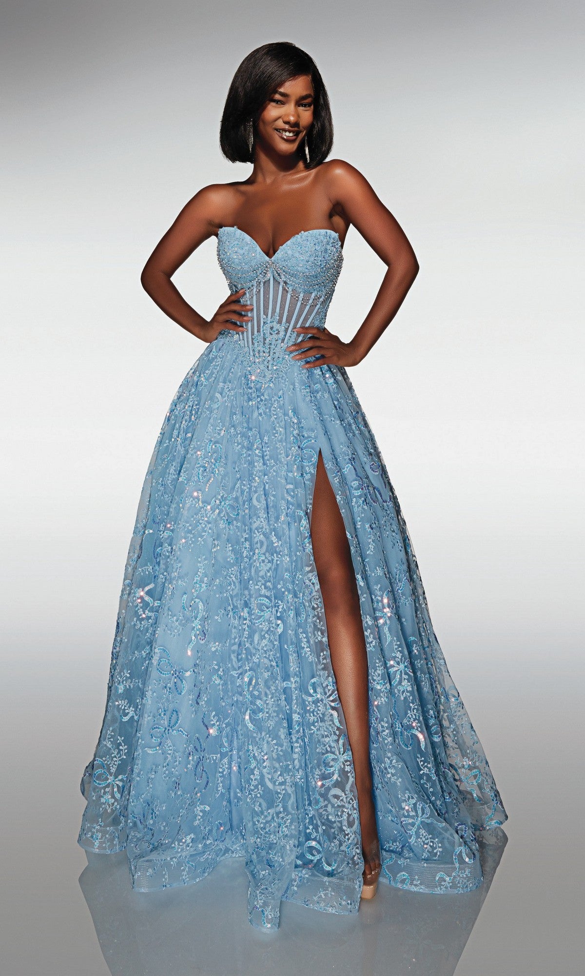 Woman wearing the Alyce 62033 long formal dress—a strapless, light blue, floor-length gown with a beaded corset bodice, floral embellishments, and a thigh-high slit—stands smiling with hands on hips.